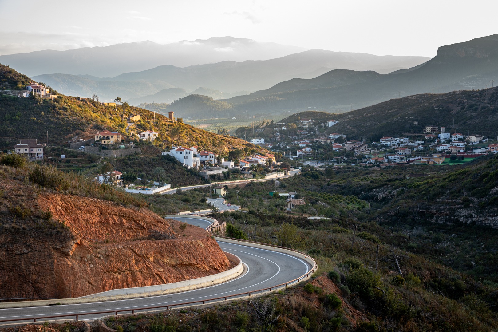 Winding road leading to a Spanish mountain village and fading mountains in the background